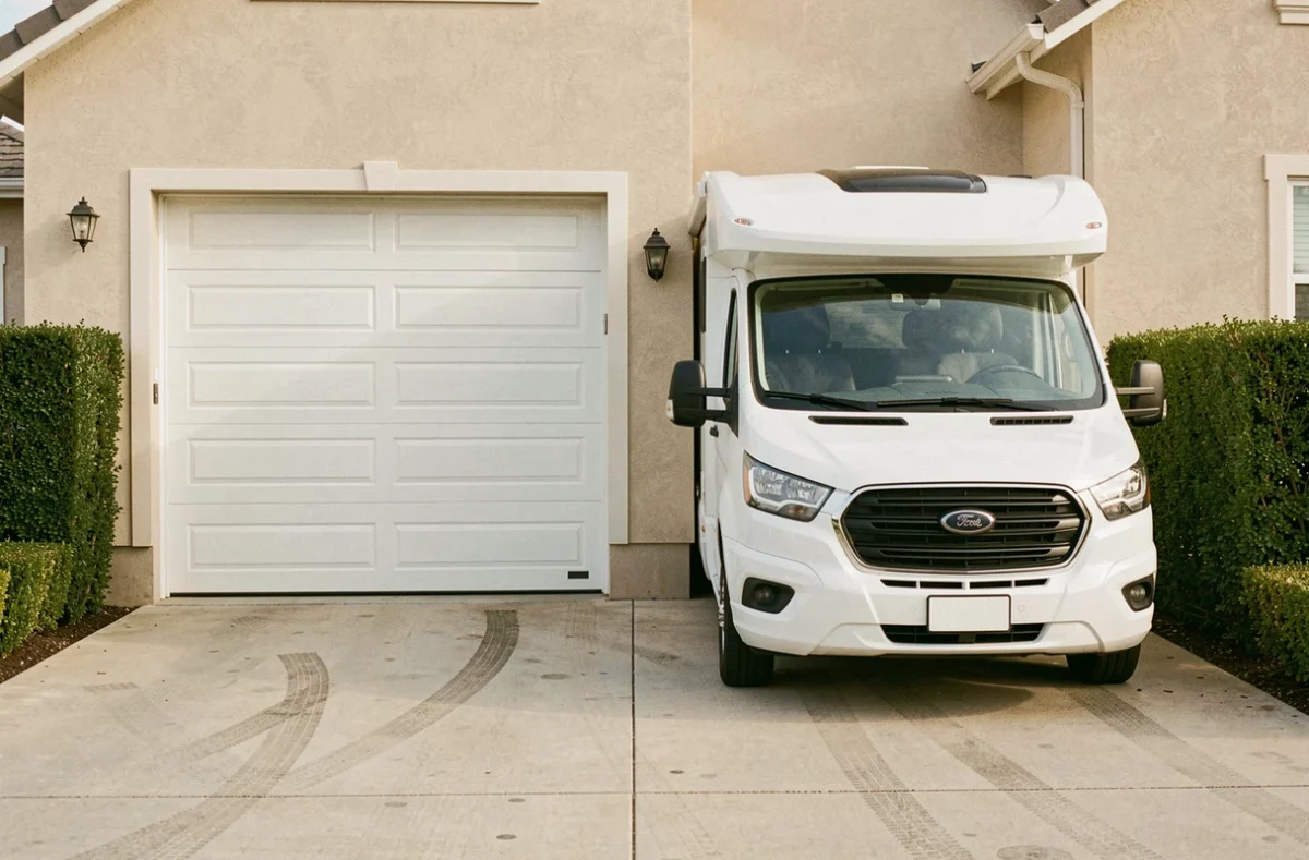 Comparaison visuelle entre la largeur d'une porte de garage et les dimensions extérieures d'un camping-car en stationnement